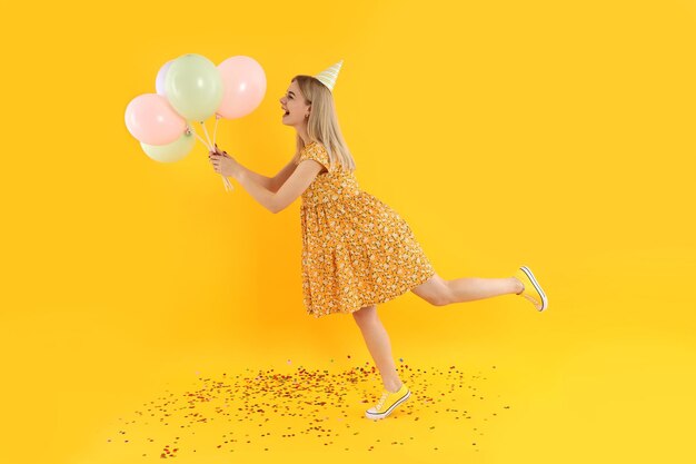 Concept of Happy Birthday with young woman on yellow background