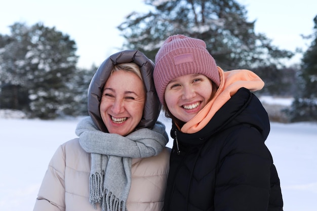 Concept of happy family old age emotions walk in the winter forest of mom and adult daughter hugging