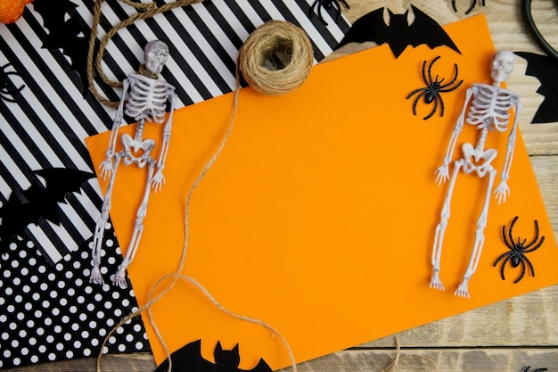 Foto il concetto di una felice vacanza di halloween. decorazioni di halloween, pipistrelli, scheletro su sfondo arancione. un mock-up di un biglietto di auguri di halloween con un posto da copiare.