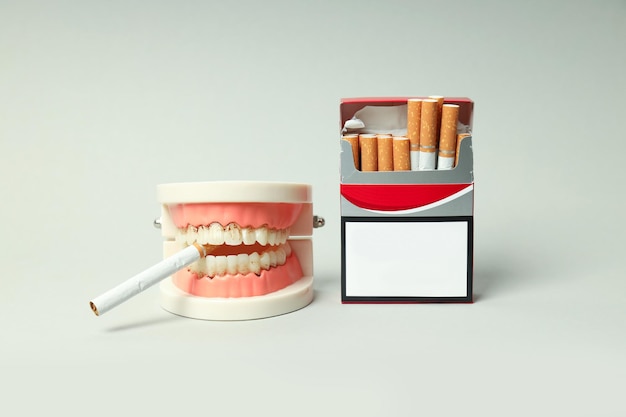 Concept of harm of smoking for teeth on light background