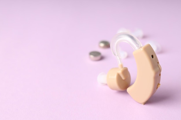 Concept of health care with hearing aid on purple background