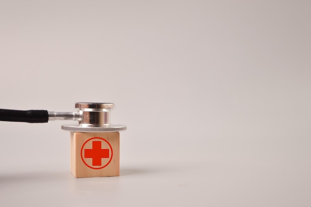 Concept of healthcare Stethoscope and wooden block with healthcare symbol