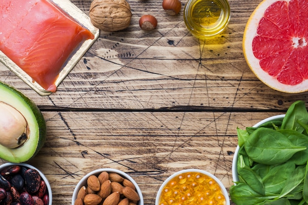 Концепция здоровой пищи антиоксидантных продуктов: рыба и авокадо, орехи и рыбий жир, грейпфрут на деревянных фоне. Копировать пространство
