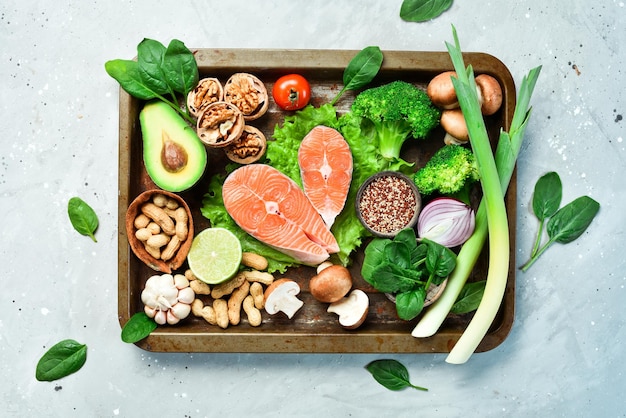 The concept of healthy food nuts salmon avocados spinach mushrooms berries On a stone background Top view Copy space