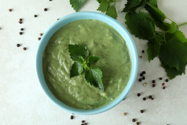 Concept of healthy food with nettle soup on white textured table