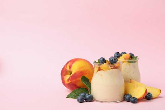 Concept of healthy food with peach yogurt on pink background