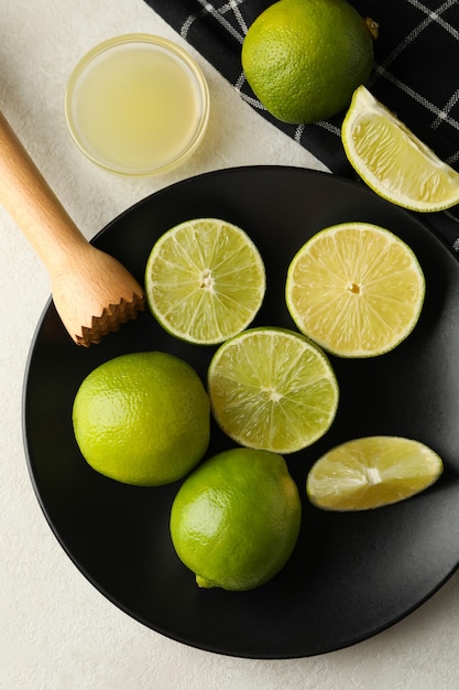 Concept of healthy food with ripe limes on white textured background