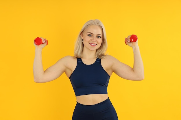 Concept of healthy lifestyle with sporty woman on yellow background