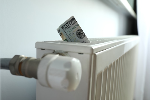 Concept of heating season with banknote in heating radiator.