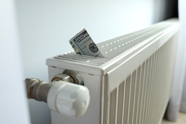 Concept of heating season with banknote in heating radiator.