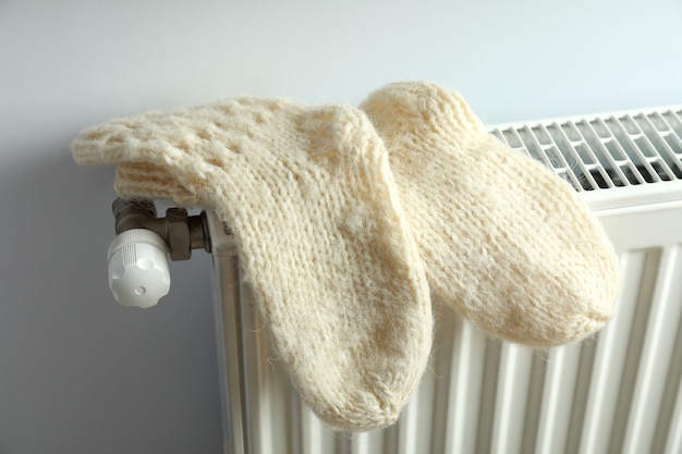 Concept of heating season with knitted socks on radiator.