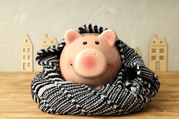 Photo concept of heating season with piggy bank on wooden table.