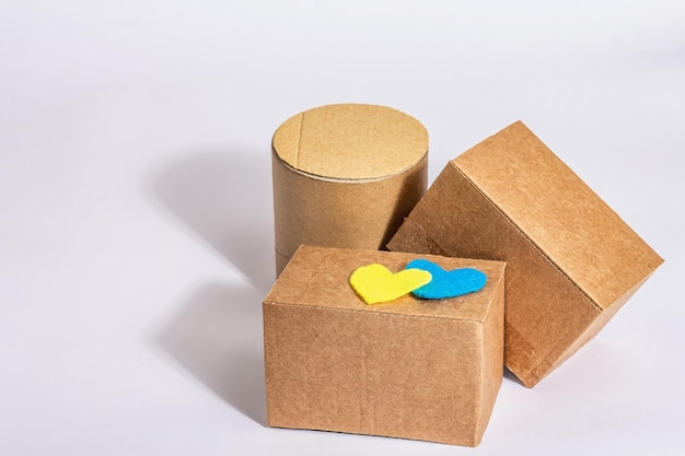 The concept of helping Ukraine in the war Boxes with hearts in the colors of the Ukrainian flag isolated on a white background Modern hard light dark shadow