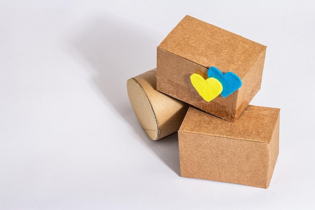 The concept of helping Ukraine in the war Boxes with hearts in the colors of the Ukrainian flag isolated on a white background Modern hard light dark shadow