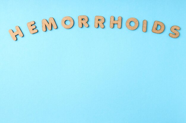 Concept of hemorrhoids with wooden letters on blue background