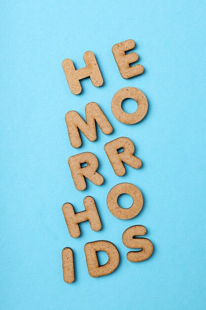 Concept of hemorrhoids with wooden letters on blue background