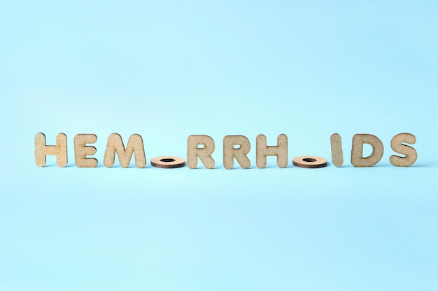 Concept of hemorrhoids with wooden letters on blue background