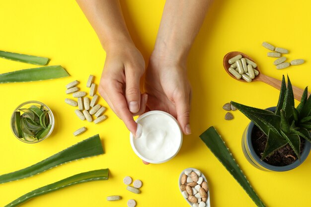 Photo concept of herb pills and cosmetics with aloe on yellow background