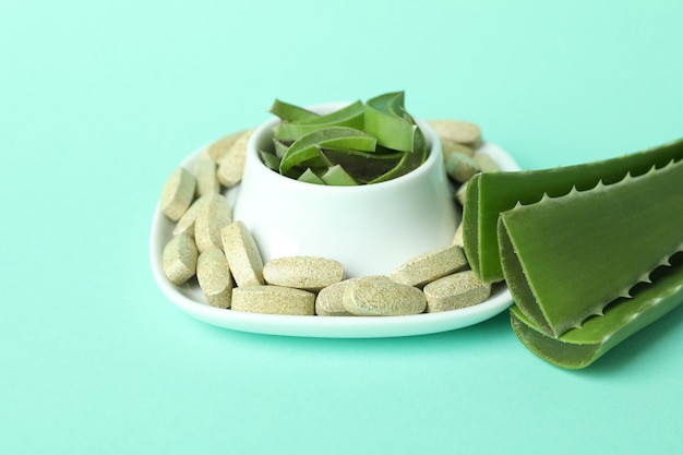 Concept of herb pills with aloe on mint background