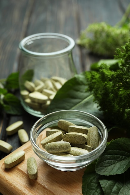 Concept of herbal medicine pills on wooden table, close up