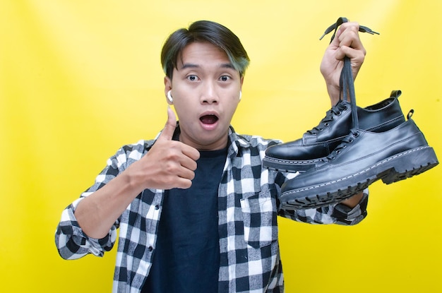 concept of home shopping A trendy Asian man carrying a phone and a pair of shoes