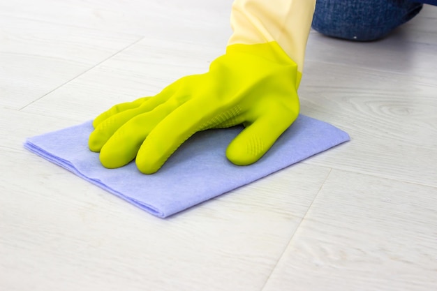 The concept of homework and cleaning. Gloved hands cleaning floor.