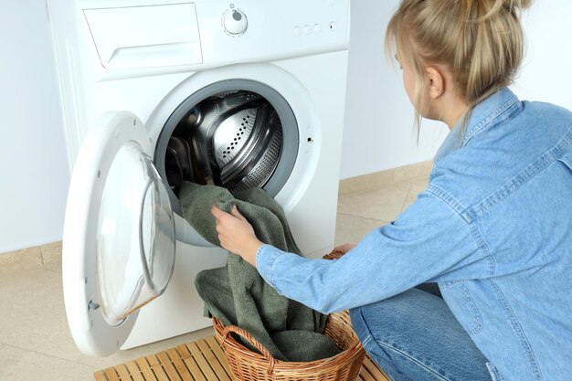 Concept of housework with washing machine and girl against white wall