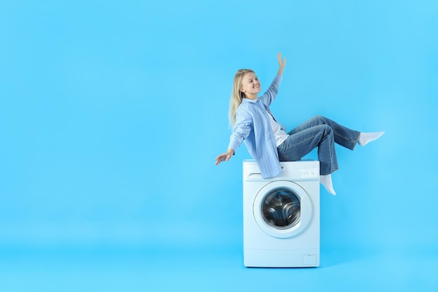 Concept of housework with washing machine and girl on blue background