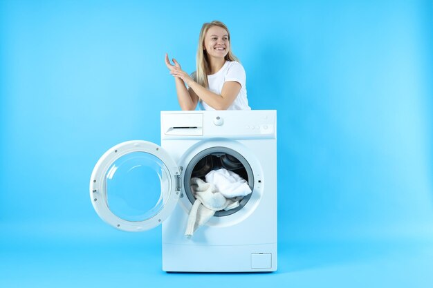 Concept of housework with washing machine and girl on blue background