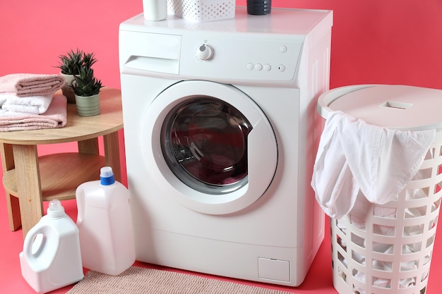 Concept of housework with washing machine on pink background