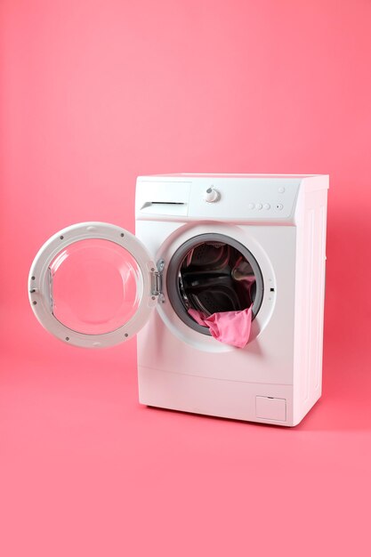 Concept of housework with washing machine on pink background