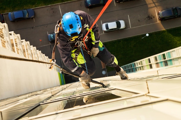 Concept of industry urban works top view industrial\
mountaineering worker hangs over residential facade building during\
high rise cleaning work