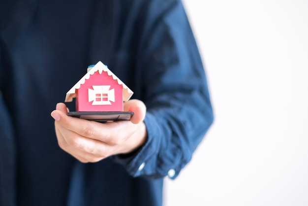 The concept of insurance property, hands holding a small house toy and protect the real estate