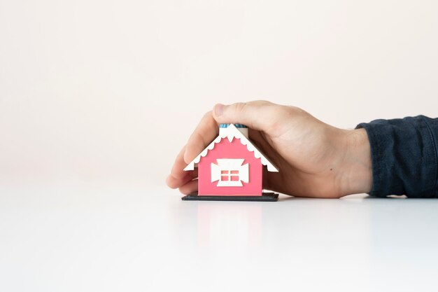 The concept of insurance property, hands holding a small house toy and protect the real estate