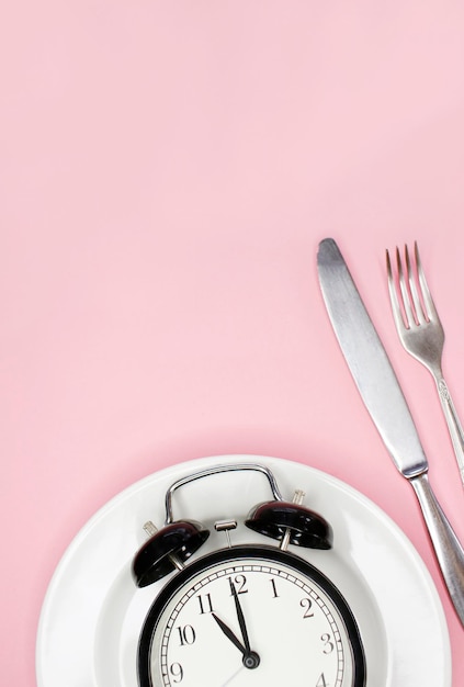 Foto concetto di dieta chetogenica a digiuno intermittente per la perdita di peso con forchetta e coltello sveglia sul piatto