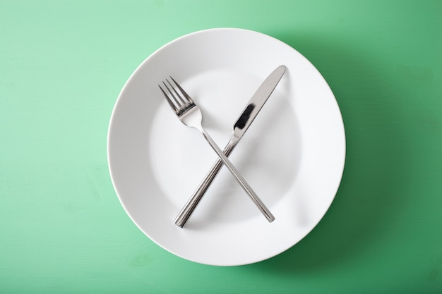 Concept of intermittent fasting and ketogenic diet, weight loss. fork and knife crossed on a plate