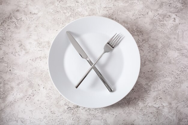 Понятие о прерывистом голодании и кетогенной диете, похудении. вилка и нож скрещены на тарелке