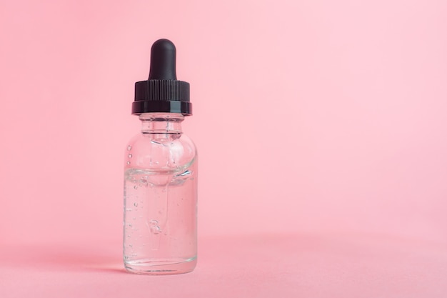 The concept is a bottle of hyaluronic acid without inscriptions on a pink background