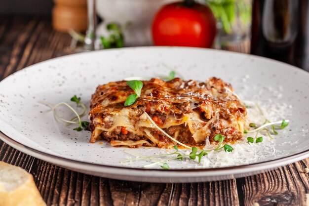 The concept of Italian cuisine. Lasagna with minced meat, bechamel sauce and parmesan cheese. Close up. Serving dishes in a restaurant in a white plate. copy space