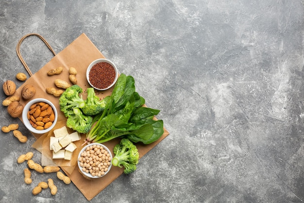 Concept: Koop gezond schoon voedsel. Eiwitbron voor vegetariërs: groenten, noten en peulvruchten bovenaanzicht op een betonnen ondergrond met een papieren zak.