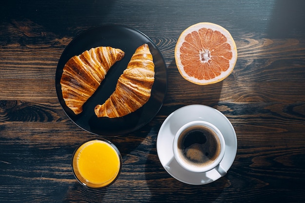 The concept of a large and varied breakfast Two croissants coffee orange juice and grapefruit