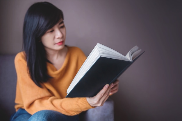 Concept lezen. vrouw ontspannen door boek zittend in een gezellige woonkamer