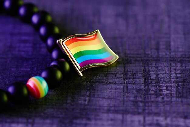 The concept of the lgbt community. a rainbow flag and a bracelet of many black and one multicolored beads on a purple background