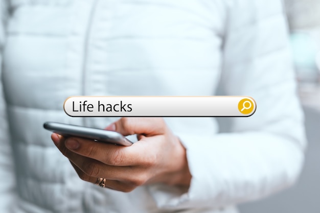 Concept life hacks in the search bar on the background of a woman with phone.