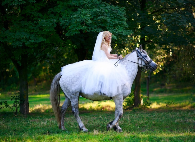 Foto concetto di matrimonio ed emozione. sposa a cavallo nella foresta