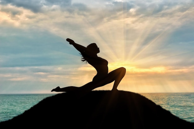 Concept of meditation and relaxation. Silhouette of a girl practicing yoga class on a background of sea sunset