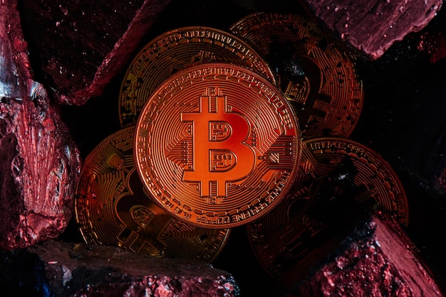 the concept of mining virtual currency. bitcoins on a black coal background close up
