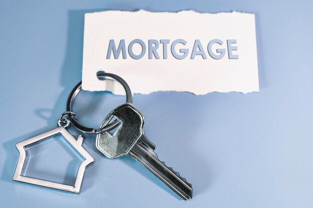Концепция ипотечной продажи и аренды жилья и недвижимости Ипотечное кредитование Брелок в виде дома с ключом на синем фоне