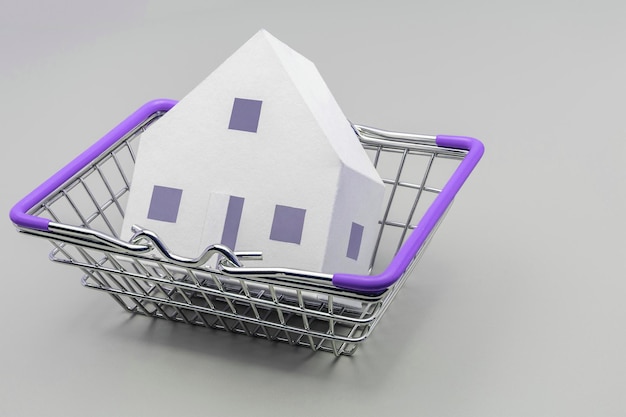 The concept of mortgage sale and rental of housing and real estate mortgage credit lending a mockup of a paper house lying in a basket from a store on a gray background banner format copy space