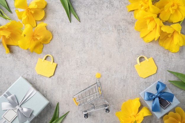 Concetto di festa della mamma, shopping regalo, design di auguri con bouquet di fiori di tulipano giallo su sfondo grigio